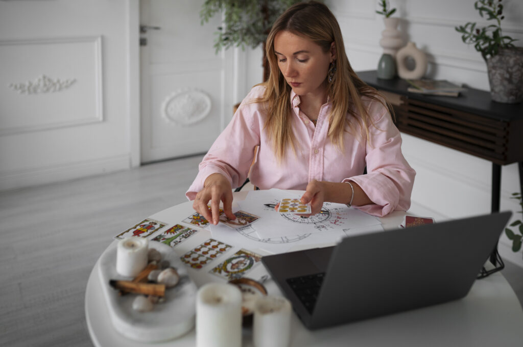 medium shot woman reading tarot with laptop